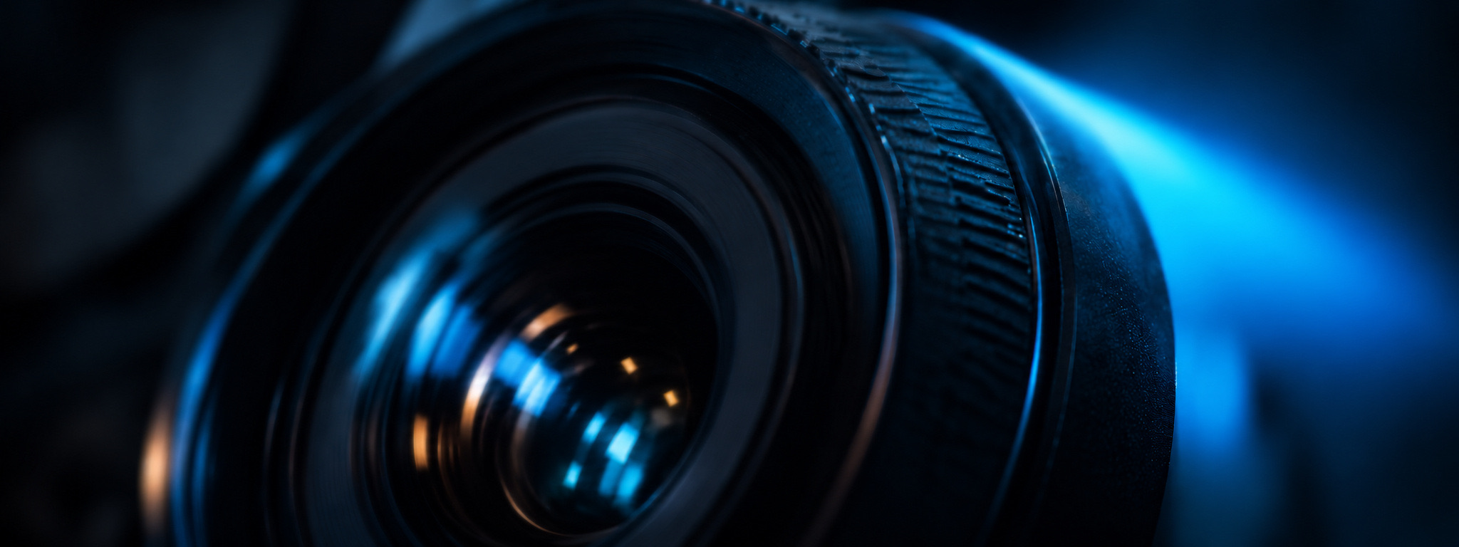Close-up of a camera lens glowing in blue light